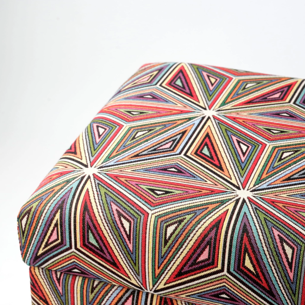 Ein farbenfroher Pouf mit floralem Motiv und Stauraum, gepolstert, auf dunklen Beinen