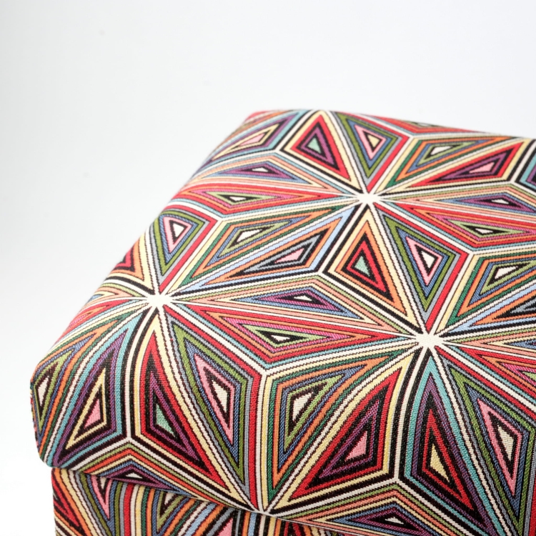 Ein farbenfroher Pouf mit floralem Motiv und Stauraum, gepolstert, auf dunklen Beinen