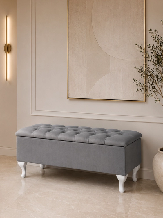 Ein gesteppter Koffer mit Sitzfläche auf weißen Beinen, ideal für den Flur