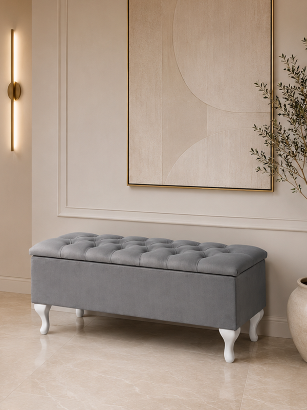 Ein gesteppter Koffer mit Sitzfläche auf weißen Beinen, ideal für den Flur